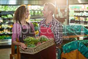 Smiling staffs holding basket of vegetable in organic section