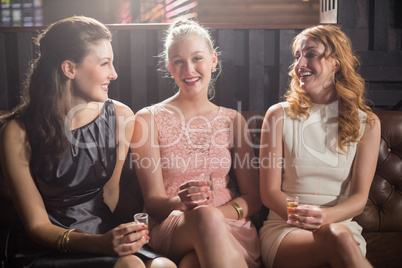 Three female friends holding shot glass of tequila in bar