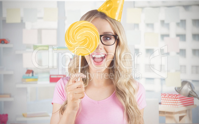 Composite image of portrait of a hipster hiding herself behind a lollipop