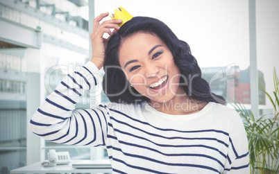 Composite image of smiling asian woman with paper crown