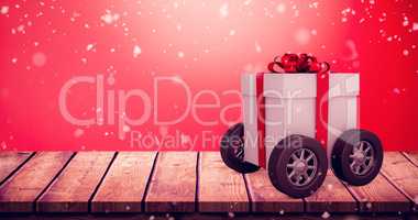 Composite image of gift box with red ribbon on wheels