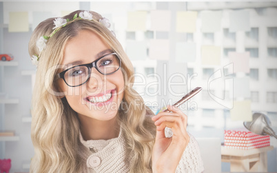 Composite image of gorgeous smiling blonde hipster holding pen