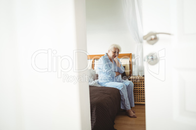 Worried senior woman sitting on bed