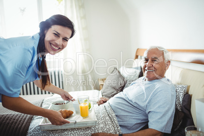 Nurse serving breakfast to senior man