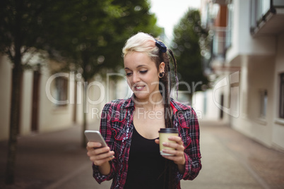 Woman using mobile phone while having coffee