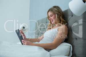 Woman using digital tablet on bed