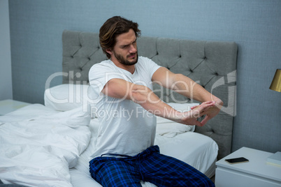 Young man waking up in bed and stretching his arms