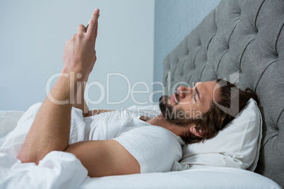 Man using mobile phone in bedroom