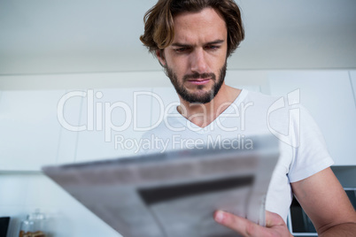 Man reading newspaper in kitchen