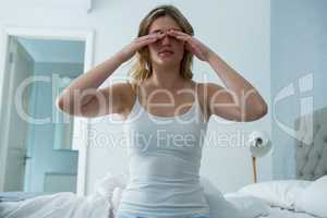 Young woman waking up from sleep in bedroom