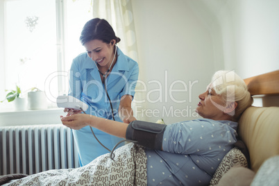 Nurse checking blood pressure of senior woman