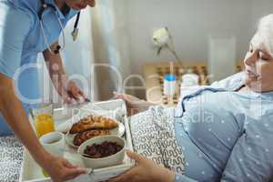 Nurse serving breakfast to senior woman