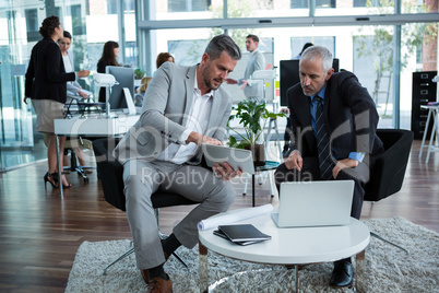 Businesspeople discussing over digital tablet