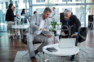 Businesspeople discussing over digital tablet