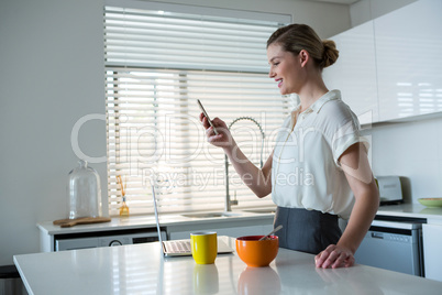 Woman using mobile phone in kitchen