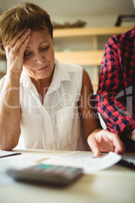 Worried senior woman looking at bills