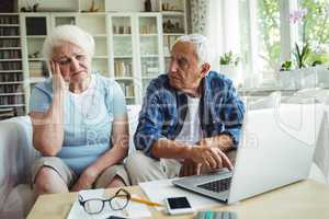 Worried senior couple using laptop