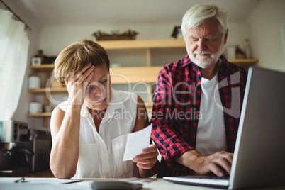 Senior couple paying bills online on laptop
