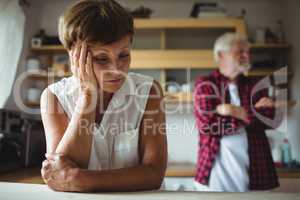 Worried senior woman leaning on table