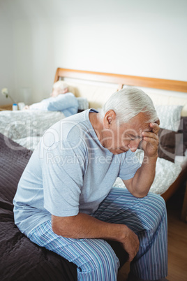 Frustrated senior man sitting on bed