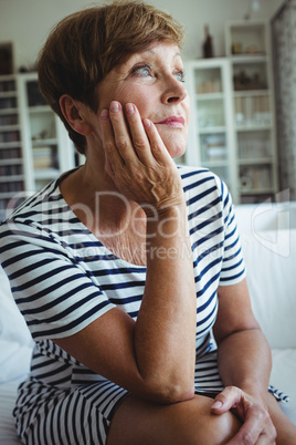 Thoughtful senior woman sitting on sofa in living room Thoughtful senior woman sitting on sofa in living room