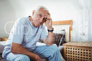 Frustrated senior man sitting on bed