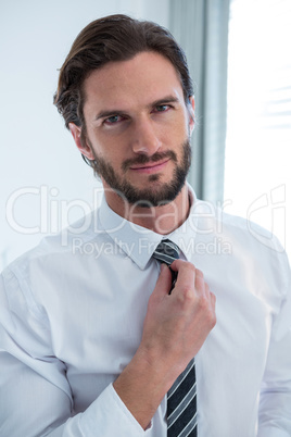 Man adjusting a tie in bedroom