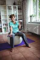 Senior woman exercising with dumbbells on exercise ball