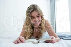 Woman lying on bed and reading novel