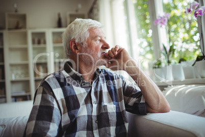 Thoughtful senior man sitting on sofa