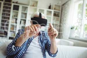 Senior man wearing virtual reality headset in living room