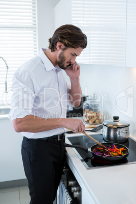 Man talking on mobile phone while preparing food in kitchen