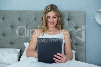 Woman using digital tablet on bed