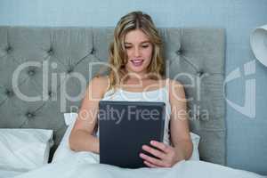 Woman using digital tablet on bed