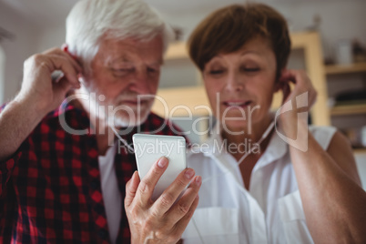 Senior couple listening to music on smartphone