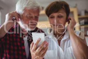 Senior couple listening to music on smartphone