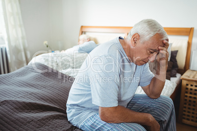 Frustrated senior man sitting on bed