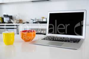 Breakfast bowl with coffee mug and laptop in kitchen