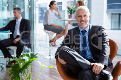 Smiling businessman sitting on chair in office