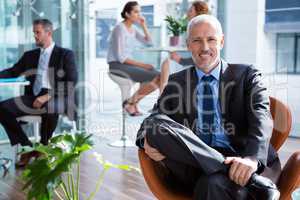 Smiling businessman sitting on chair in office