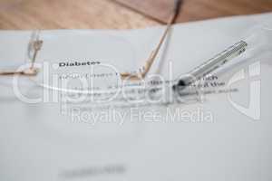 Close-up of injection with diabetes test paper and spectacle