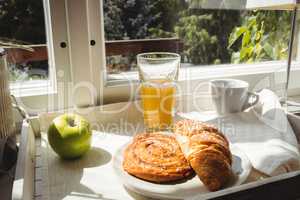 Close-up of croissant and glass of juice on a tray