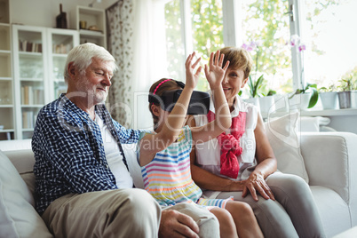 Granddaughter using virtual reality headset with her grandparents in living room
