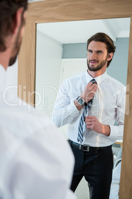 Man getting dressed in bedroom while looking at mirror