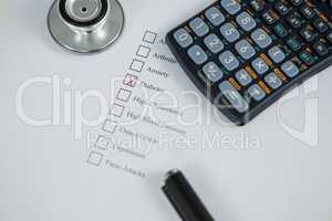 Close-up of health evaluation form with diabetes check and calculator, stethoscope