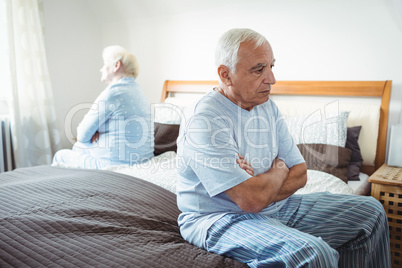 Sad senior couple sitting on bed