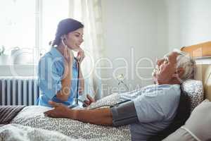 Nurse checking blood pressure of senior man