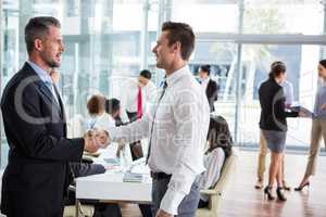 Businessmen shaking hands in office