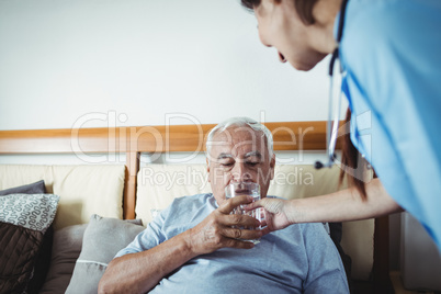 Nurse giving a glass of water to senior man