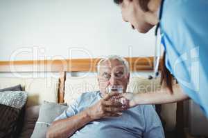 Nurse giving a glass of water to senior man